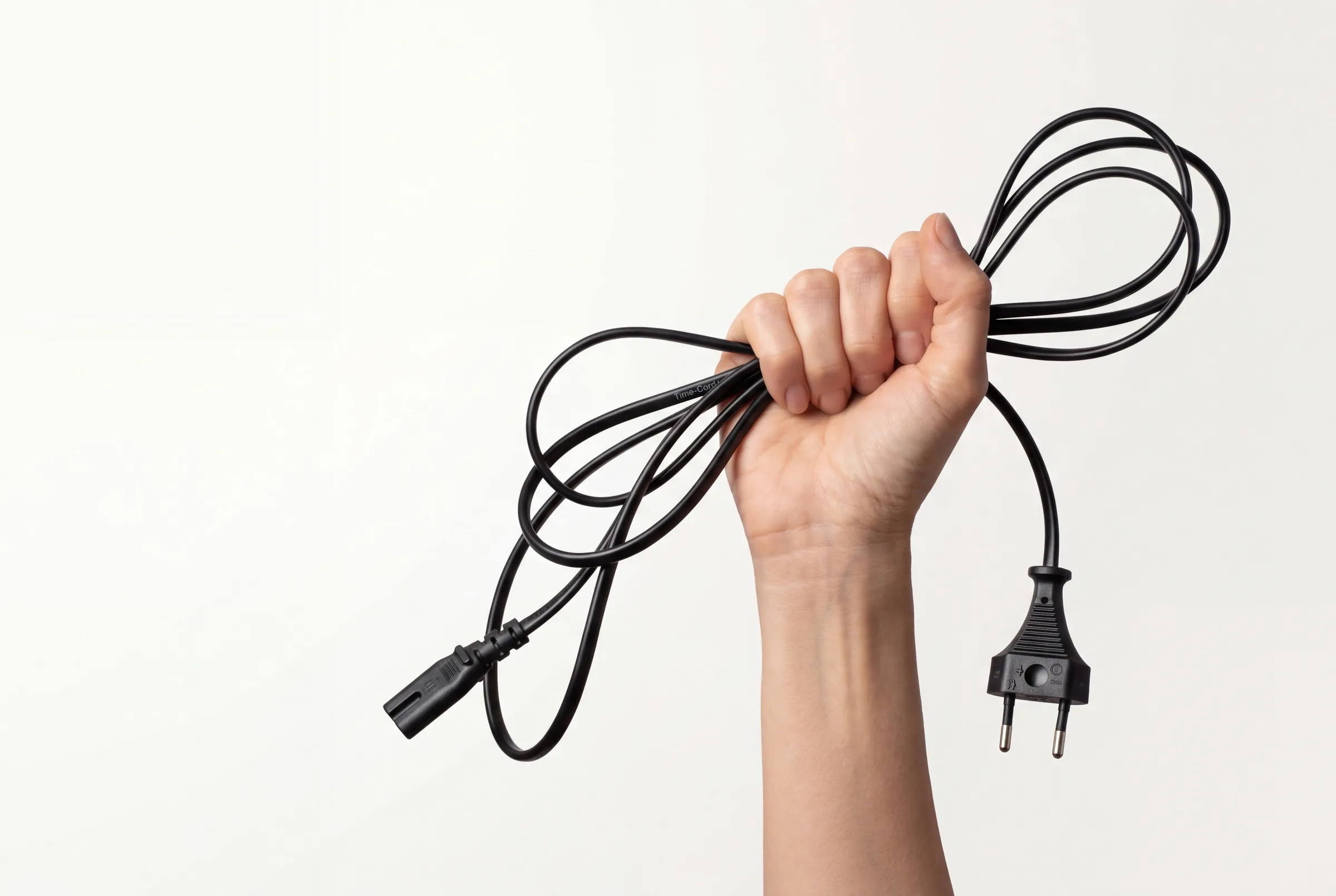 A raised fist holding an ordinary-looking black Time-Cord power cord with a Euro plug